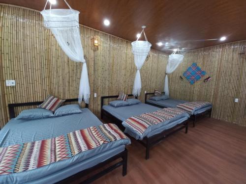 two twin beds in a room with a wall at Dong Que Homestay-Tours-Motorbike, Car rental, Hiking in Ha Giang