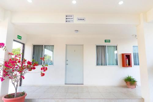a white room with a door and flowers at Hotel Nápoles in Ciudad Obregón