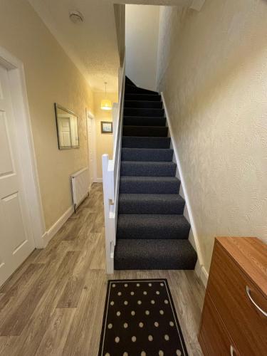 a hallway with stairs with a rug and a stair case at Spacious 2-Level Home by the Beach & Transport in Methil