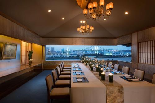 a long table in a restaurant with a view of the city at Hilton Tokyo Odaiba in Tokyo