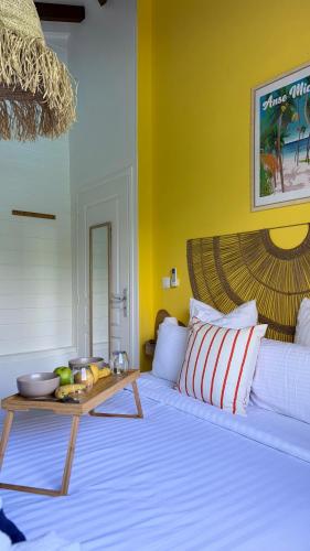 a bedroom with a white bed with a table on it at La Maison Caraïbes in Sainte-Anne