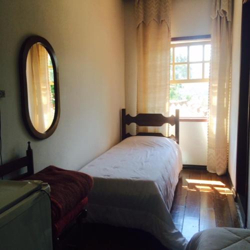a bedroom with two beds and a mirror and a window at Pousada Recanto Das Pedras in Tiradentes