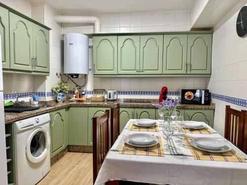 a kitchen with green cabinets and a table with plates at Apartamento Alcázar San Basilio in Córdoba