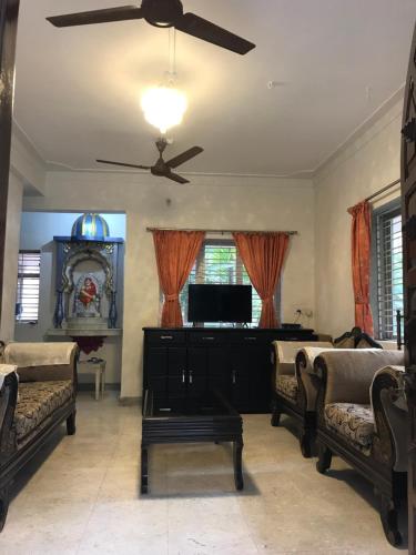 a living room with couches and a ceiling fan at Vaishali bungalow Nagaon in Nagaon