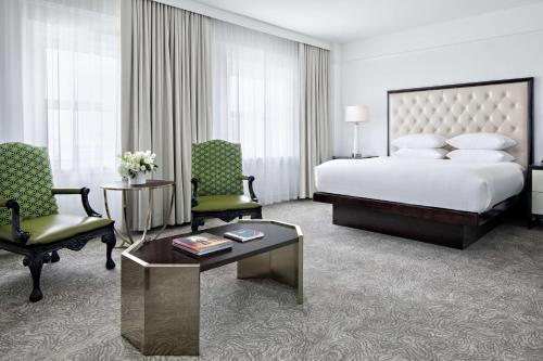 a hotel room with a bed and two chairs at Amway Grand Plaza Hotel, Curio Collection by Hilton in Grand Rapids