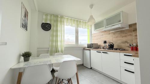 a kitchen with white cabinets and a table and chairs at Apartament KOREK in Stronie Śląskie