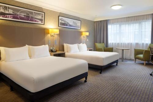 a hotel room with two beds and a chair at DoubleTree by Hilton Glasgow Central in Glasgow