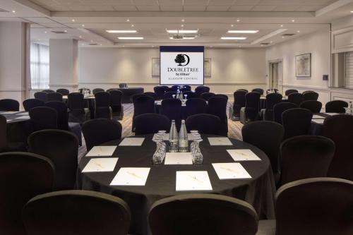 a conference room with tables and chairs and a screen at DoubleTree by Hilton Glasgow Central in Glasgow