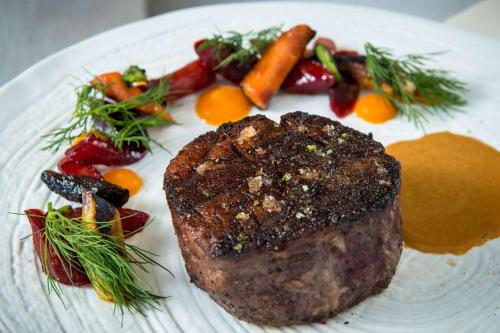 a white plate with a piece of meat and vegetables at Waldorf Astoria Beverly Hills in Los Angeles