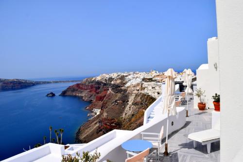 a view of the ocean from a balcony with white chairs at Captain John Villas Oia - Caldera & Sunset View in Oia
