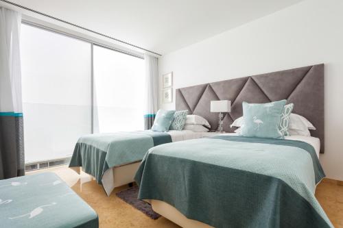 a bedroom with two beds with green and white sheets at Pine Cliffs Village in Albufeira