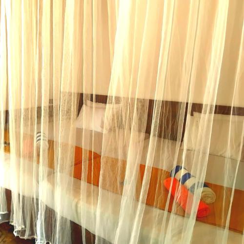 a bedroom with a bed with white curtains at gramatic dream cottage in Udawalawe