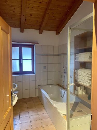a bathroom with a bath tub and a window at Landhaus Maiergschwendt inkl Chiemgaukarte in Ruhpolding