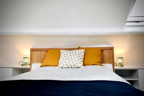 une chambre avec un lit avec des oreillers jaunes dans l'établissement Charmante maisonnette à 2 pas de la plage !, à Étretat