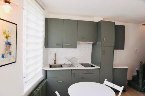 - une cuisine avec des placards gris, un évier et une table dans l'établissement Charmante maisonnette à 2 pas de la plage !, à Étretat