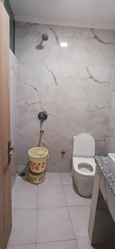 a bathroom with a toilet and a bucket in it at The Royal Metropolitan IGI Airport Delhi in New Delhi