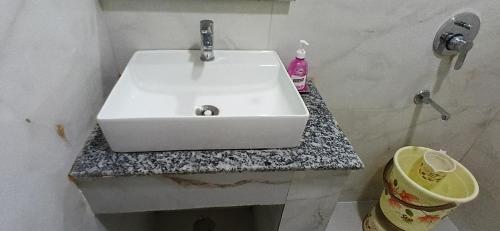 a white sink in a bathroom with a trash can at The Royal Metropolitan IGI Airport Delhi in New Delhi