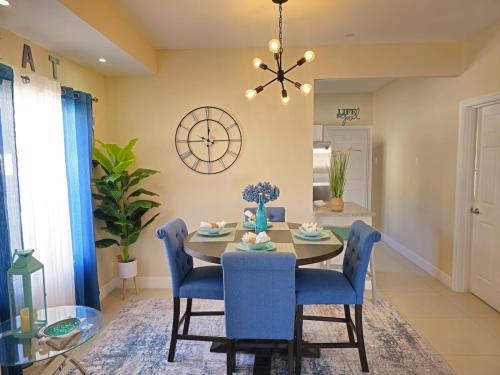 a dining room with a table and chairs and a clock at Sunny-Shore Hideaway in Lucea