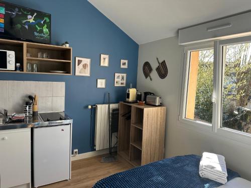 - une cuisine aux murs bleus et un lit dans une chambre dans l'établissement Les Lilas Gare Centre 2 Pers, au Mans