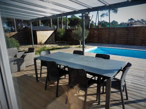 - une table et des chaises sur une terrasse à côté de la piscine dans l'établissement bee free, à Montalivet-les-Bains