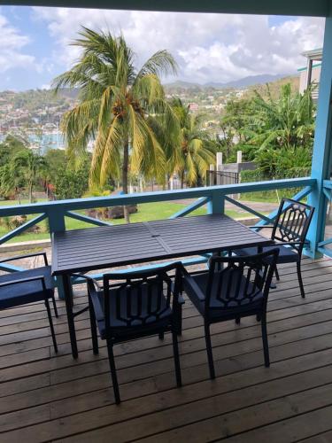 a wooden table and chairs on a deck with a view at CasaCalypso Grenada in Belmont