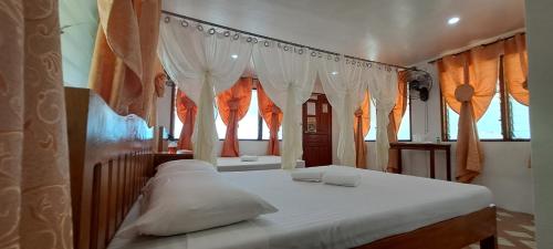 a bedroom with a bed with white curtains at Chilly Beach Resort Palawan in Aborlan