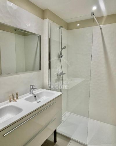 une salle de bain avec un lavabo et une douche en verre dans l'établissement La Petite Plage, à Merlimont