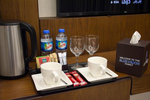 a table with two glasses and a bottle of water at Blue Moon Hotel in Erbil