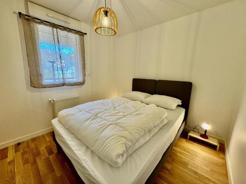 a bedroom with a large bed with white sheets and a window at Appartement 4 à 5 personnes au bord du lac in Génos