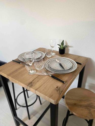 une table en bois avec des assiettes et des verres à vin dessus dans l'établissement Studio Cosy Centre de Reims, à Reims