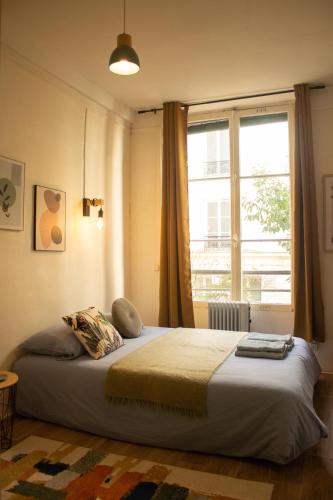 une chambre avec un lit avec une grande fenêtre dans l'établissement Saint Germain de Près tout équipé - Emplacement exceptionnel au Coeur de Paris, à Paris