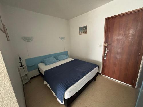 une petite chambre avec un lit et une porte en bois dans l'établissement Appartement 26m² Sud/Est avec Balcon à Balaruc-les-Bains, Animaux acceptés - FR-1-503-69, à Balaruc-les-Bains