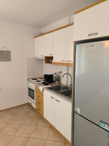 a kitchen with white cabinets and a sink and a refrigerator at Polychrono Waves in Polykhrono
