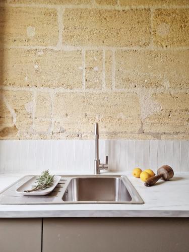- un évier de cuisine avec des fruits et des légumes sur un comptoir dans l'établissement Gîte Vin'acacia, à Saint-Romain-la-Virvée