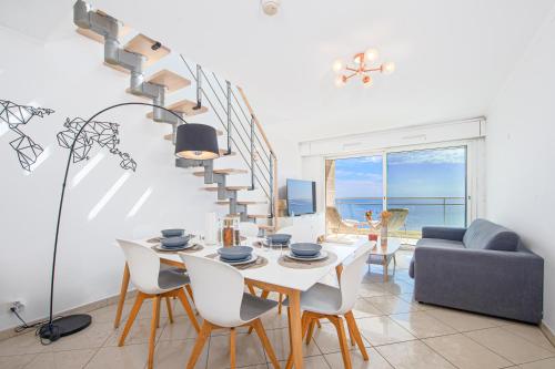 a living room with a table and chairs and a staircase at JARDINS DE MONACO - Vue Mer - Jacuzzi - Parking in Cap d'Ail