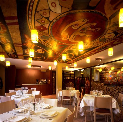 a restaurant with white tables and chairs and a ceiling at Hotel La Casueña in Lanuza