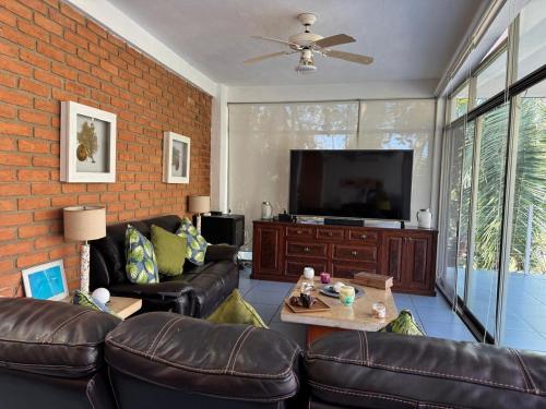 a living room with leather furniture and a flat screen tv at Casa Mismaloya Selva in Cedro