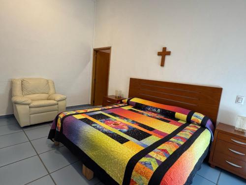 a bedroom with a bed and a chair and a cross on the wall at Casa Mismaloya Selva in Cedro