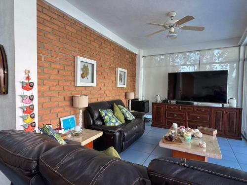 a living room with a leather couch and a flat screen tv at Casa Mismaloya Selva in Cedro