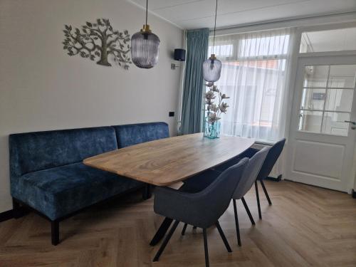 a dining room with a blue couch and a wooden table at Modern spacious holiday home within walking distance of the North Sea beach in De Koog in De Koog