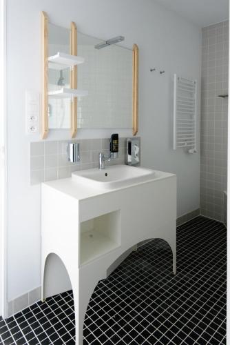 a white bathroom with a sink and a mirror at Hôtel Belvue in Brussels