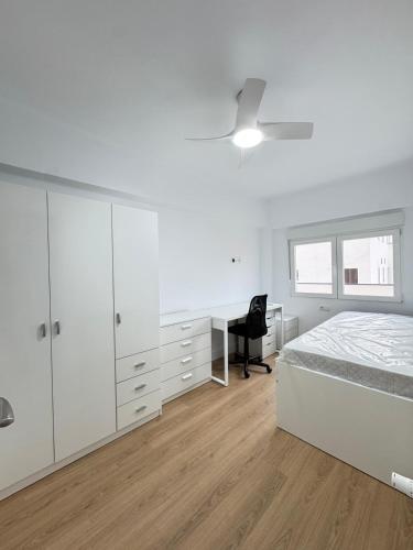 a white bedroom with a bed and a desk at Nohe in Cuenca