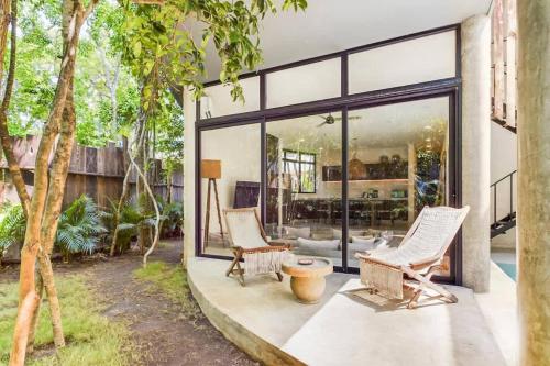 a patio with two chairs and a table and windows at Boho Jungle Villa -Pvt Pool -Concierge-Hammock 7B in Tulum