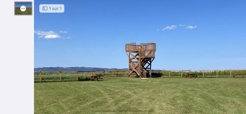 a field with two benches and a wooden tower at Chalets Nautika in Gaspé