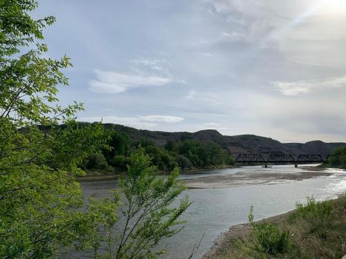 a river with a train bridge in the distance at Spacious Drumheller-RetreatMuseum & Golf in Drumheller