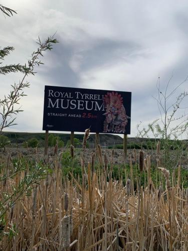 a sign in the middle of a field with tall grass at Spacious Drumheller-RetreatMuseum & Golf in Drumheller