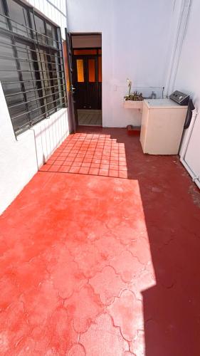 an empty room with a red floor and a door at Gardenia Roof Hostel in Aguascalientes