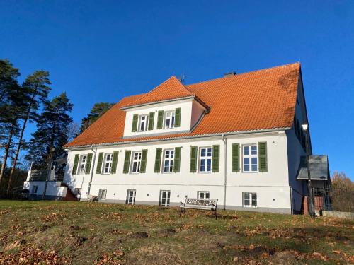 a large white house with an orange roof at Leśniczówka Szeroki Bór in Szeroki Bór
