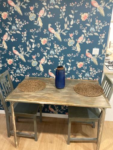 une table en bois avec deux chaises devant un mur avec papier peint à fleurs dans l'établissement Maison du lavoir, à Villemur-sur-Tarn