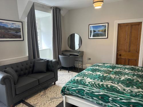 a bedroom with a bed and a couch and a mirror at Cil-y-Coed in Dolgellau